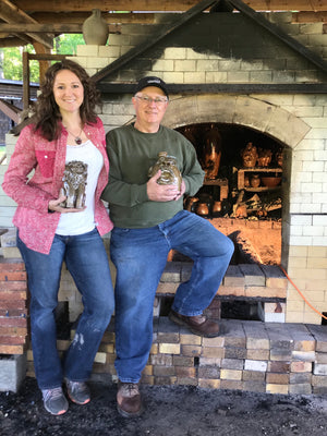 Crystal King and Father Terry King Standing with Face Jugs in front of their Wood Kiln In Seagrove NC